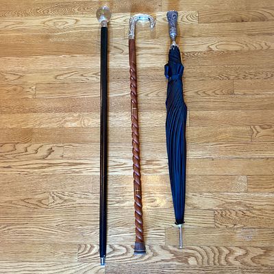 A Trio of Items Including Two Walking Canes and One Long Handle Umbrella. This lot contains two 