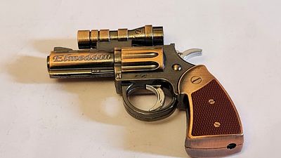 Elmeddin מצית בצורת אקדח תוף, עם כוונת סמן קרן לייזר אדום, הגוף עשוי מתכת בגוון ברונזה, הידיות 