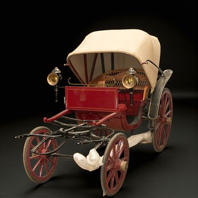 Red carriage with beige canopy. Open two-seater carriage with a polychrome red and black wooden 