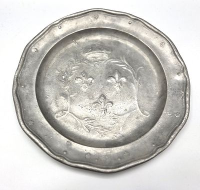 צלחת פיוטר צרפתית עתיקה, המאה ה-19, מעוצבת בדגם עגול עם שוליים מורמים ושפה גלית, מעוטרת במרכזה 