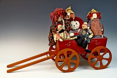 Five Rag Dolls in the Style of Raggedy Ann and Andy in a Painted Wagon. A collection of five rag 