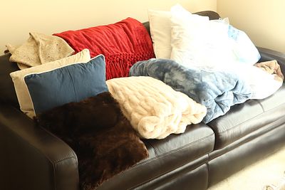 An Assortment of Five Throw Blankets, Four Pillows, and a Three Seat Leather Sofa. An assortment 