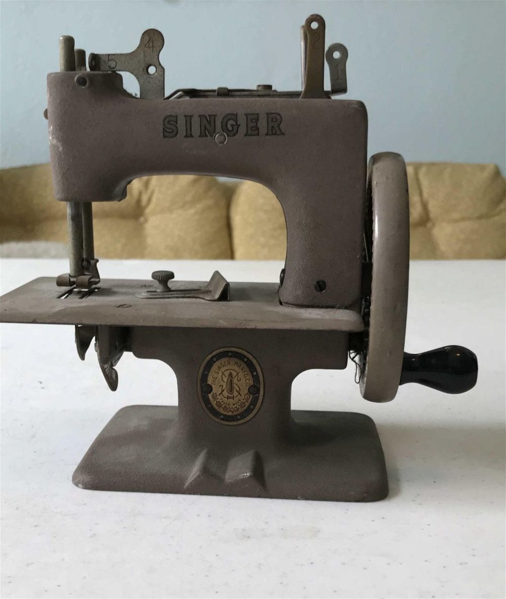 Lot 229: Vintage miniature sewing machine from the singer company measures to be 7 inches lengthwise 6 inches