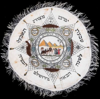 בצלאל - כיסוי למצות לליל הסדר, על פי רישום של זאב רבן, עבודת בצלאל, עשוי בד ועליו הדפסים צבעוניים. 