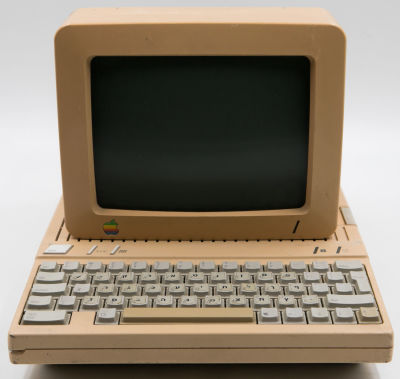 APPLE - מחשב אפל Iic APPLE הכולל מסך. גוף המחשב כולל מקלדת מובנת, כונן דיסקטים וכן ידית נשיאה. על 