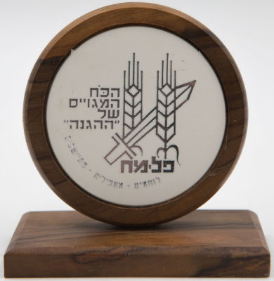 מדלית פלמ"ח מחומר פלסטי מושקעת בבסיס עץ זית. פלמ"ח - הכח המגויס של ההגנה - לוחמים, מעפילים, מתיישבים