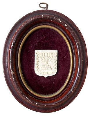 סמל המדינה, עבודת יד, מככל הנראה חומר טבעי. על גבי לבד בצבע בורדו במסגרת בצורת אליפסה, עשויה עץ 