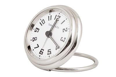 Tiffany&Co. שעון מסעות. עשוי ניקל, מנגנון קוורץ. נתון בנרתיק עור מקורי. קוטר כ- 63 מ"מ.