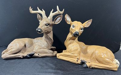 A Pair of Cast Resin Reclining Deer Figurines. A pair of decorative figurines depicting a buck 