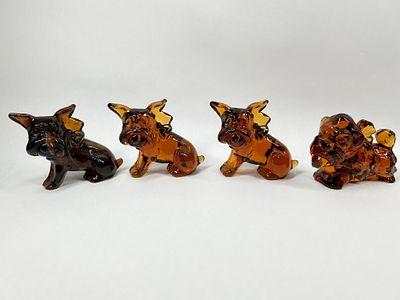 IMPERIAL PARLOR PUP AMBER GLASS DOGS. An assortment of four molded glass dog figurines in a rich 