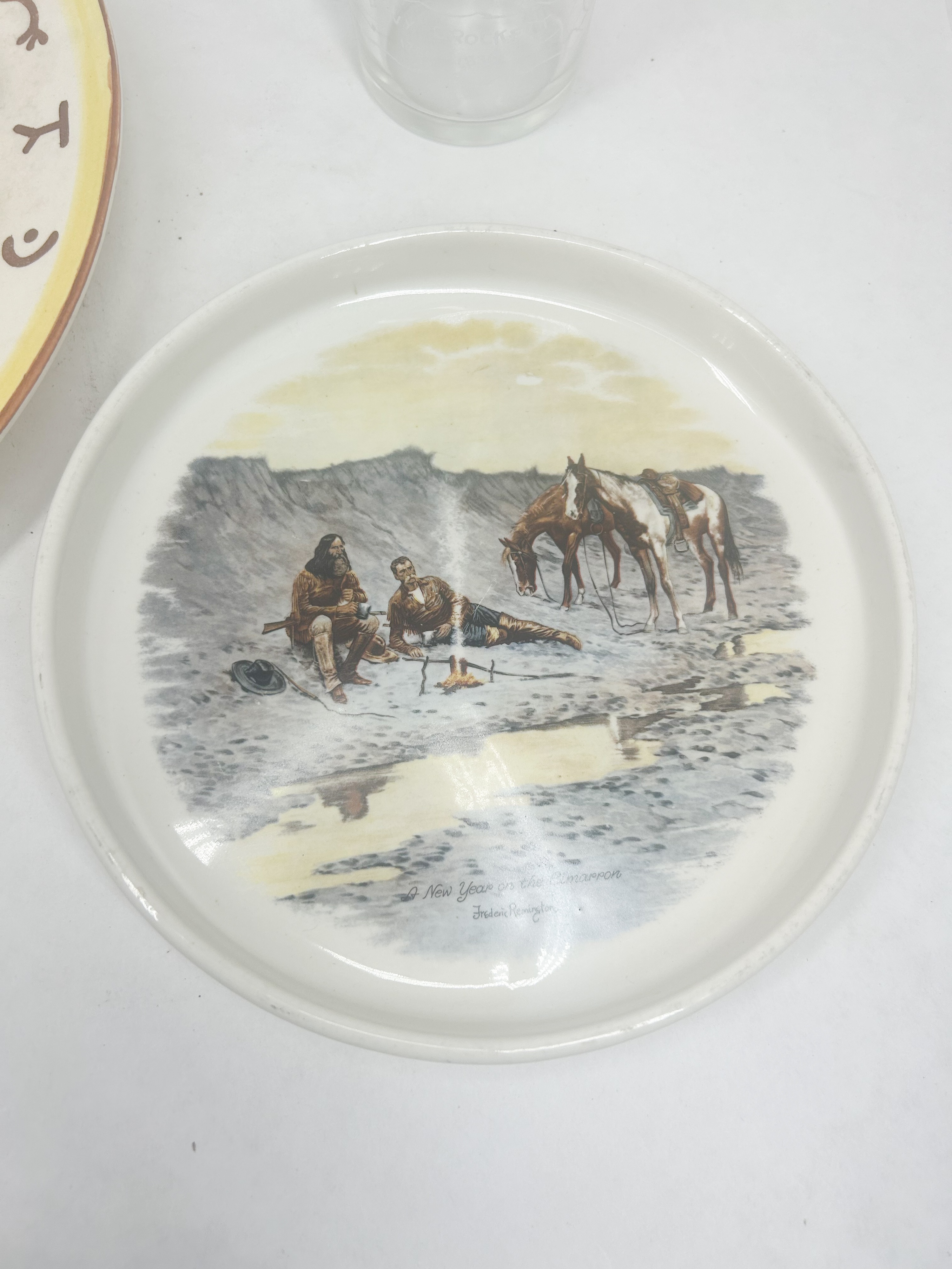 A TRIO OF CERAMIC AND GLASS WESTERN-THEMED TABLETOP ITEMS INCLUDING A FREDERIC REMINGTON PRINT DECORATED PLATE
