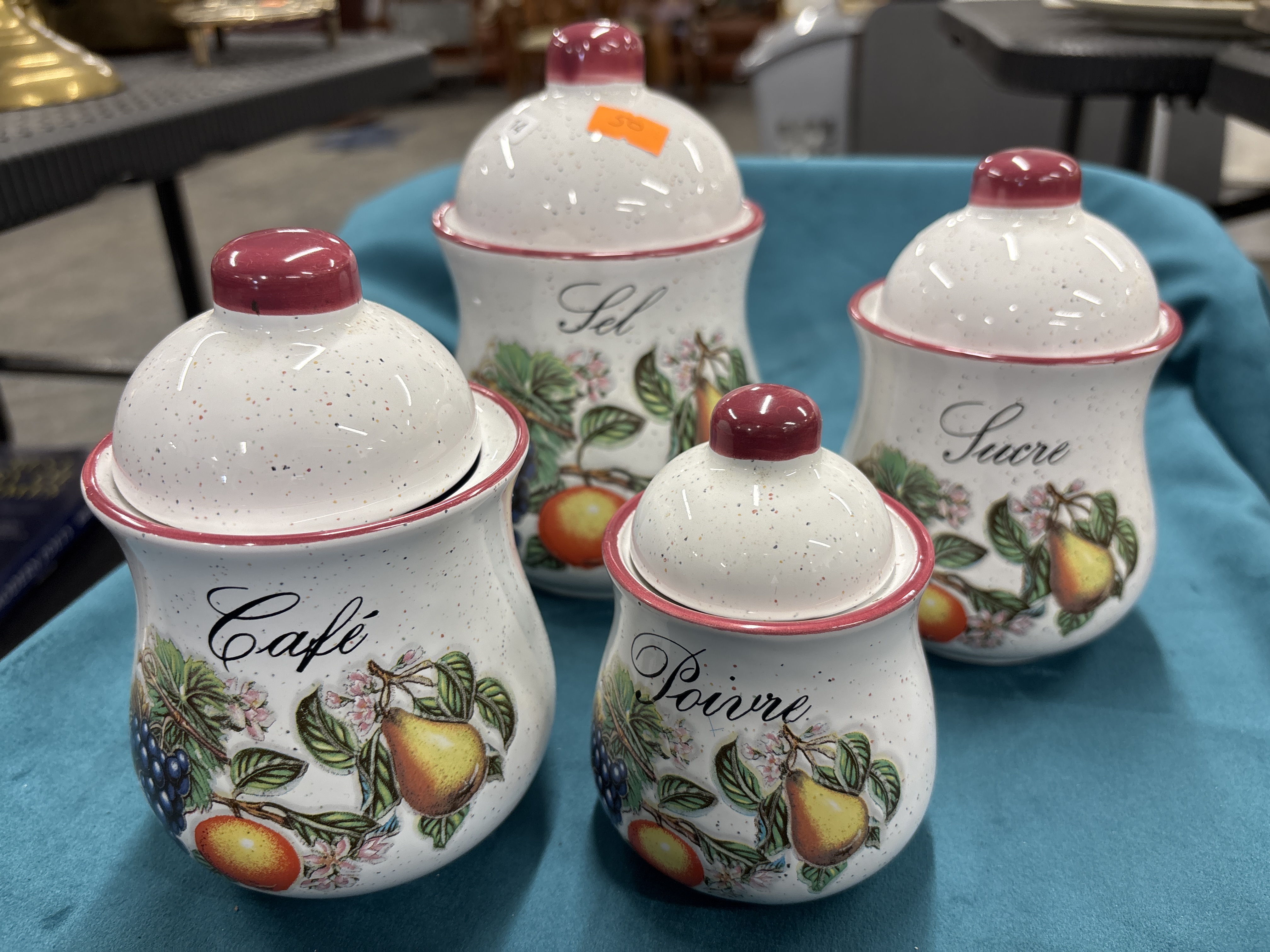 A Set of Four Graduated French-Labelled Ceramic Kitchen Canisters with Fruit Decoration