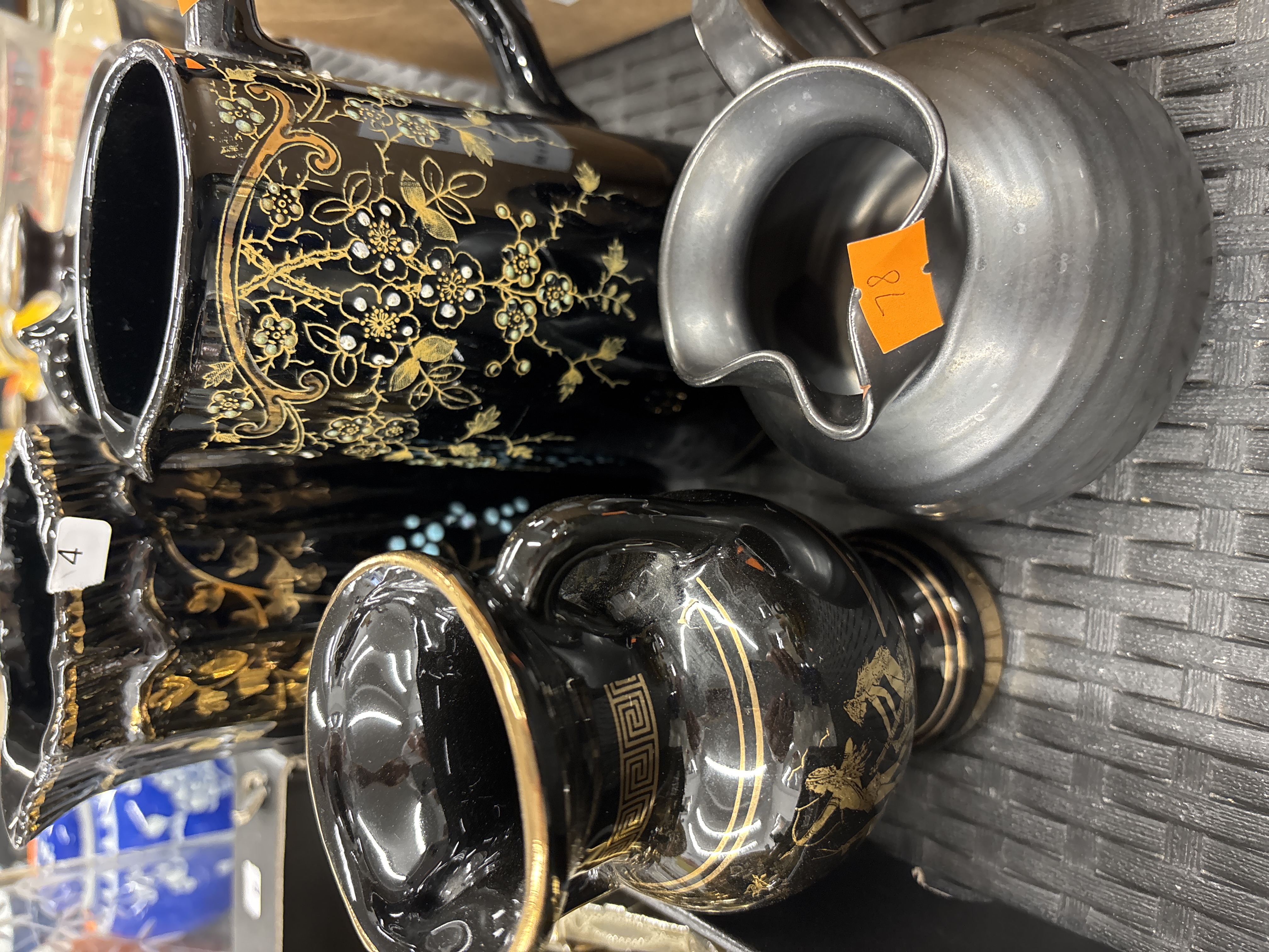 Three decorative vessels comprising two black-glazed ceramic items with gilded decoration and a matte grey metal jug