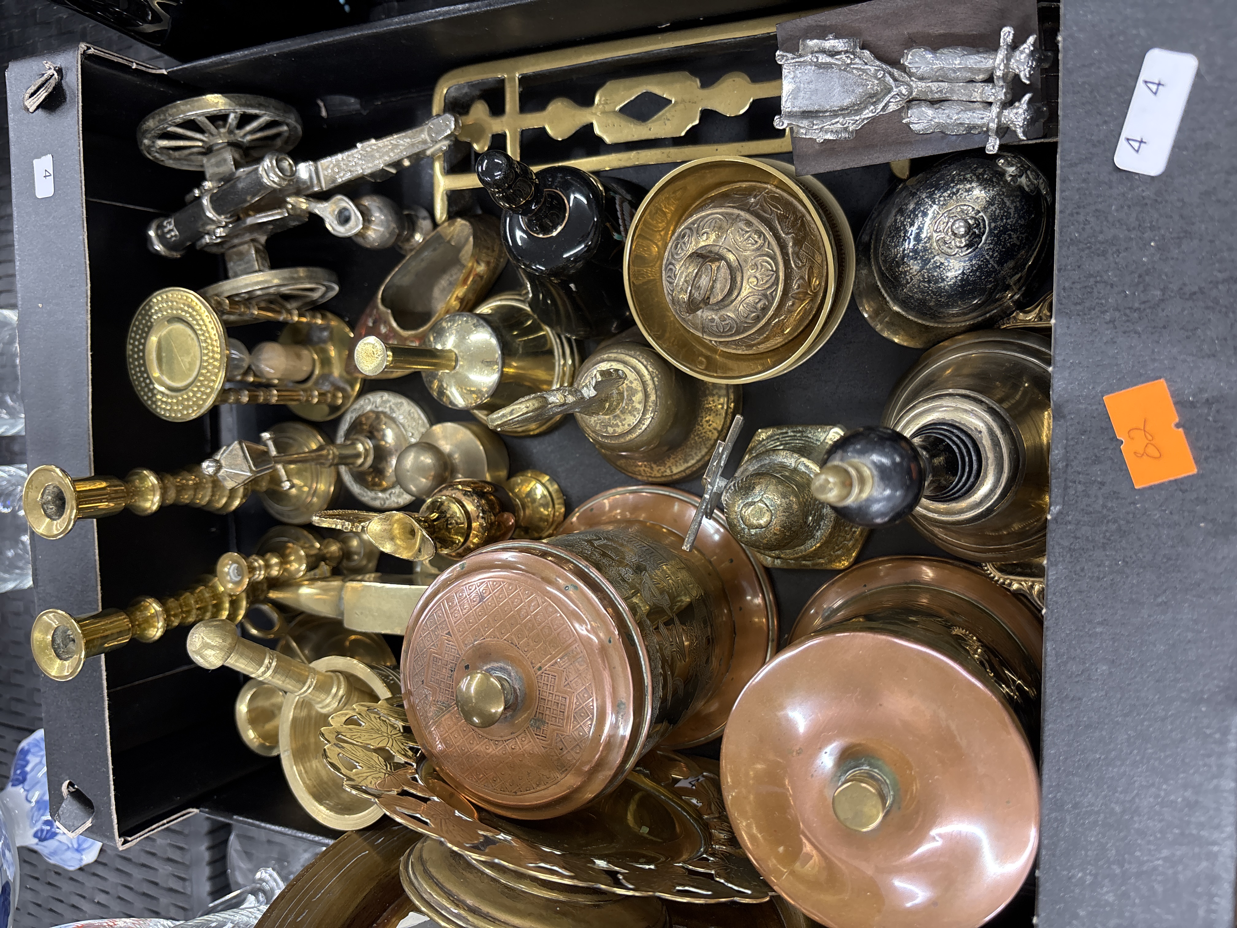 A collection of domestic brass and copper metalware including handbells, candlesticks, and chased jars