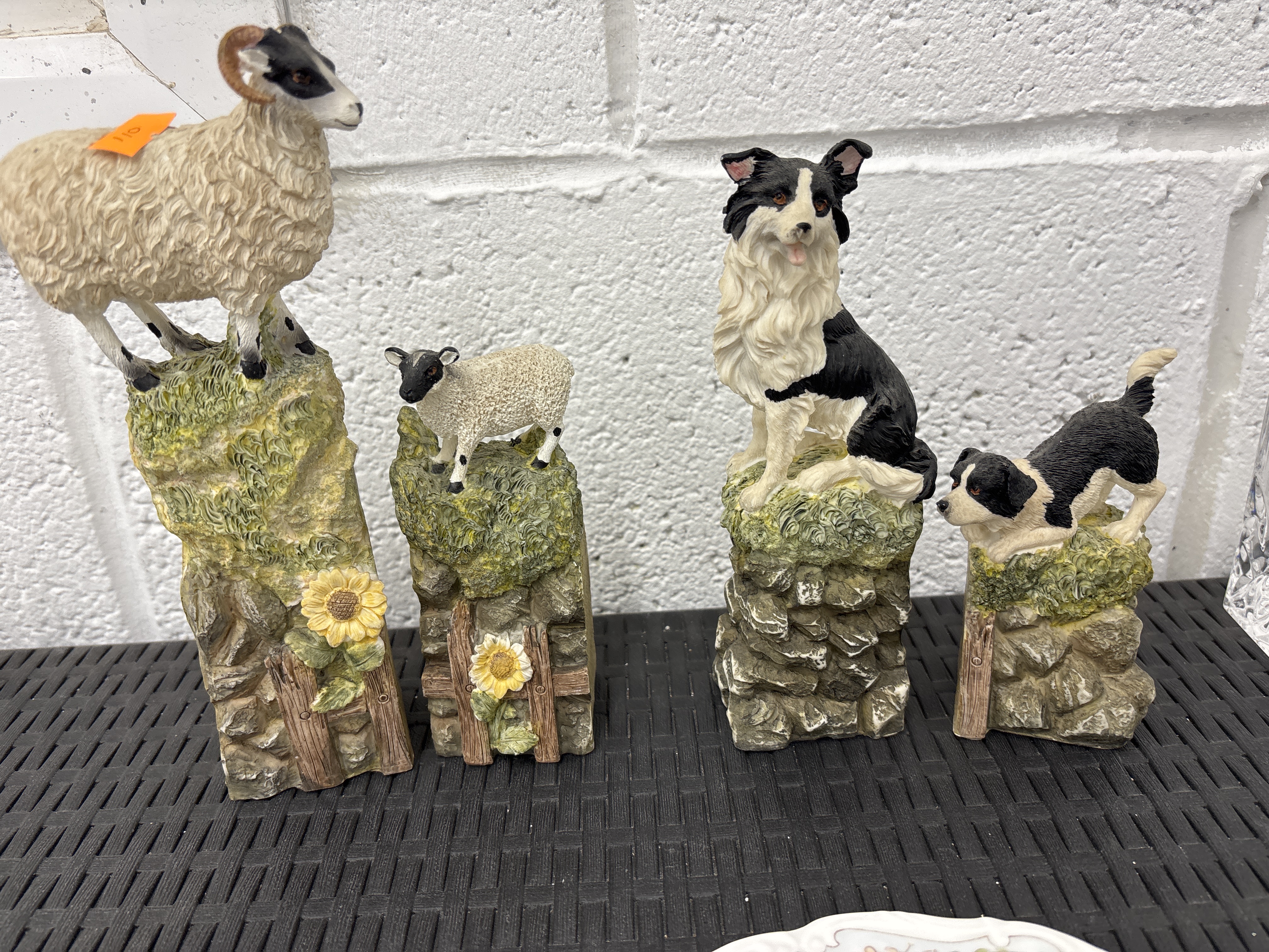 A Set of four hand-painted polyresin figurines depicting border collies and sheep