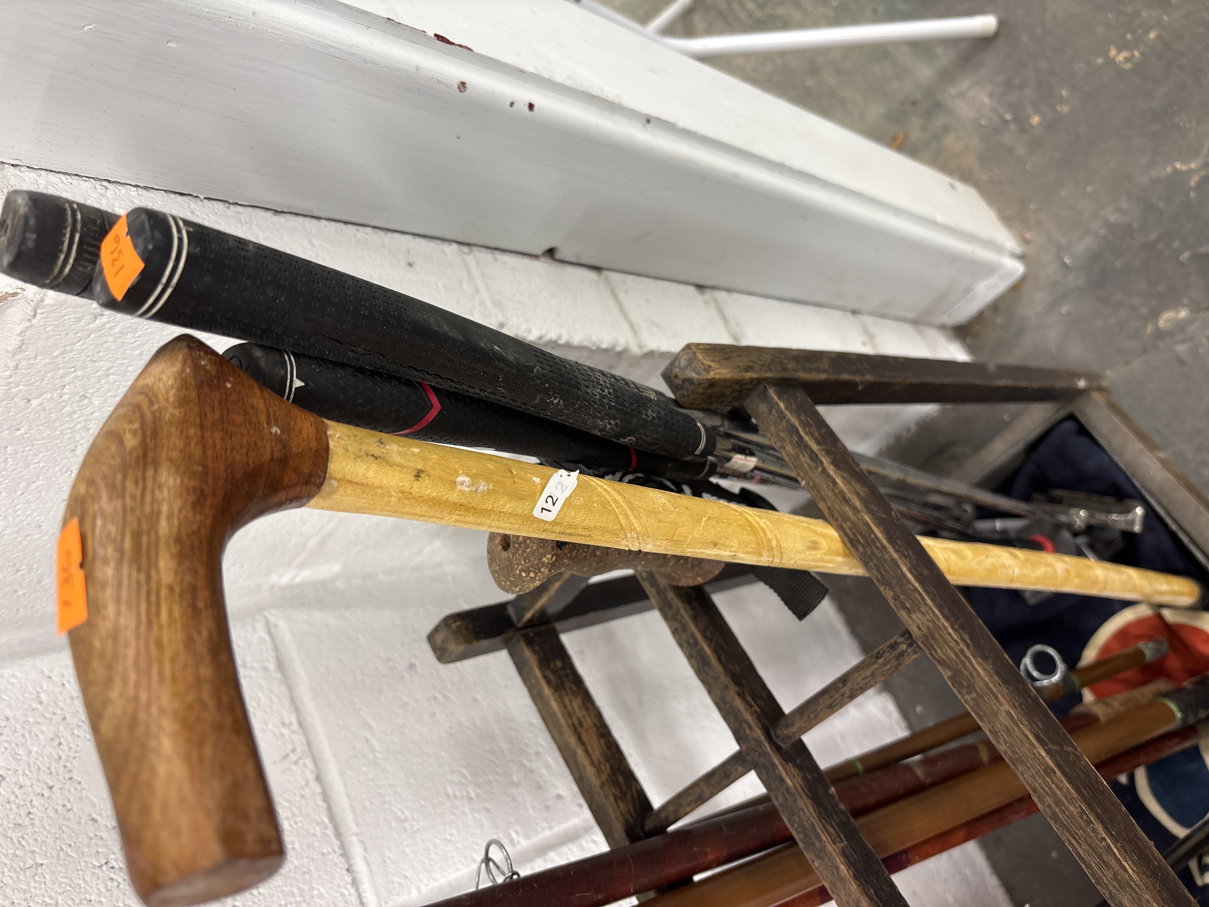 An Assortment of Golf Clubs, a Wooden Walking Cane, and a Wooden Storage Rack