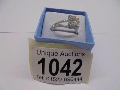 An 18ct floral diamond white gold ring with diamond shoulders. size M half, 3.1 grams.