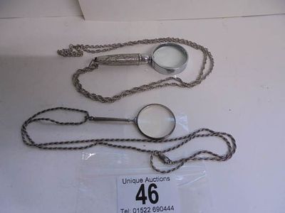 Two good magnifying glasses, one on long silver chain the other on white metal chain.