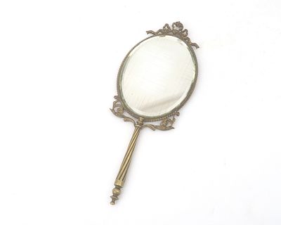 A brass Art Nouveau hand mirror A brass oval hand mirror with faceted mirror glass and a 