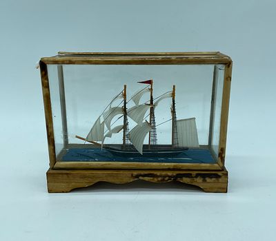 Miniature caravel with wooden base and fabric details. Caravel in glass dome with wooden