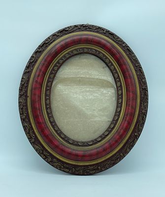 Wooden wall frame. Oval wooden wall frame in relief, textured and decorated with plant motifs.