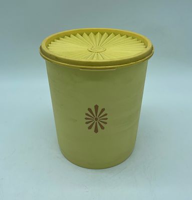 Vintage Tupperware kitchen canister with lid. Cylindrical piece in yellow plastic with graphics