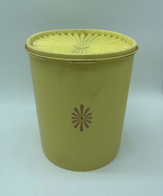 Vintage Tupperware kitchen canister with lid. Cylindrical piece in yellow plastic with graphics