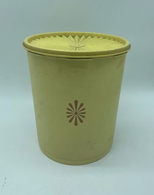 Vintage Tupperware kitchen canister with lid. Cylindrical piece in yellow plastic with graphics