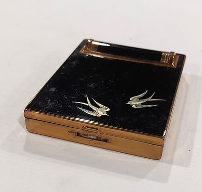 Rice Powder Box
. Rectangular body in gold-plated metal with a black lacquered lid featuring a 