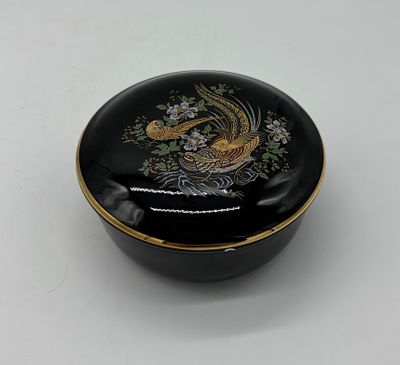 Porcelain box. Moulded and embossed porcelain box with lid. Circular black body with polychrome 