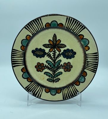 Decorative faience plate decorated with floral motifs using polychrome paint and a glazed 