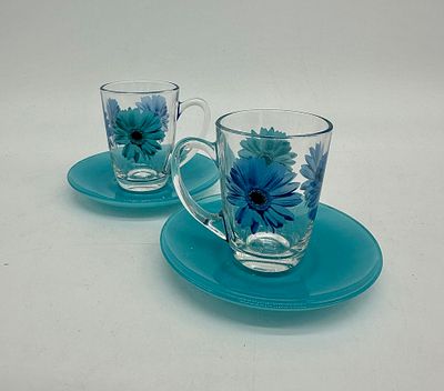 Two cups and saucers. Two glass cups with coloured glass saucers. The transparent glass cups 
