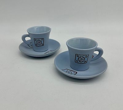 Two cups and saucers in painted porcelain. The cups feature a daisy flower and geometric 