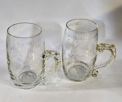 Two Glass Mugs
. Cylindrical glass bodies with a side handle, decorated with gold floral 
