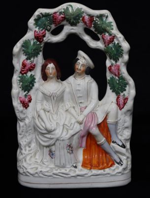 A Victorian Staffordshire group of 2 figures seated under arbour with painted grape and vine 