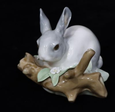 A Lladro figure of a rabbit standing on a log, 8.5cm high