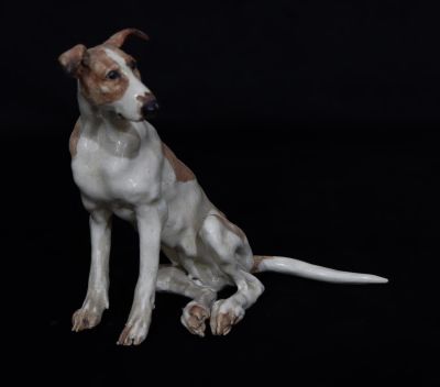 A Studio glazed earthenware figure of a seated dog on white and brown ground, indistinctly 