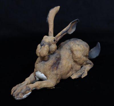 A Studio earthenware figure of a hare with glass eyes (tail restored)Tail restored